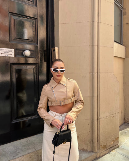 girl stood in front of black door wearing a cropped belted cream leather jacket and maxi skirt.