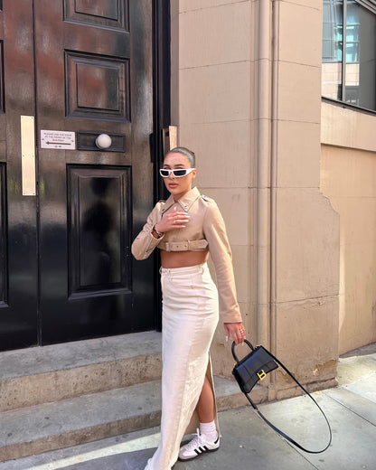 girl stood in front of black door wearing a cropped belted cream leather jacket and maxi skirt.